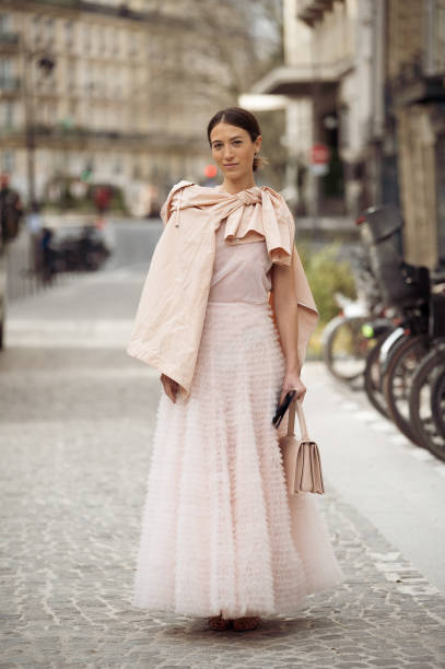 Guest wears pink tule maxi dress, beige bag and pale pink shirt outside the Akris fashion show during the Womenswear Fall/Winter 2025/2026 as part of...