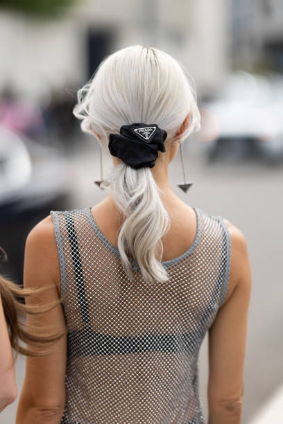 Guest wears Prada pendant earrings, a Prada black hairband, a black bra and a rhinestones fishnet silver tank top outside Prada show during the Milan...