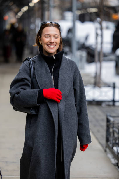 Guest wears red gloves, grey coat outside Ulla Johnson during New York Fashion Week on February 09, 2025 in New York City.