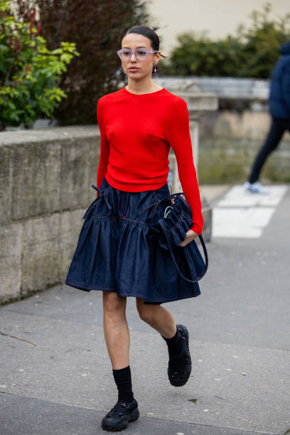 Guest wears red long shirt, dark denim skirt, bag outside Cecilie Bahnsen during the Womenswear Fall/Winter 2024/2025 as part of Paris Fashion Week...