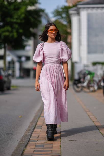 Guest wears red sunglasses, light pink puffy sleeve midi dress, silver rings, black boots leather shoes, outside Won Hundred, during the Copenhagen...