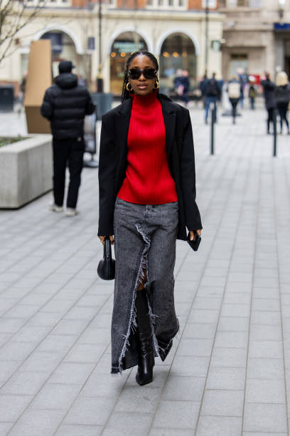 Guest wears red turtleneck, black blazer, grey denim jeans skirt with slit outside Mark Fast during London Fashion Week February 2024 on February 16,...