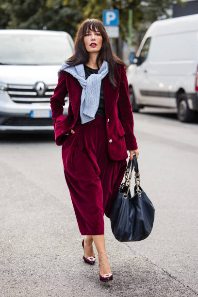 Guest wears red velvet blazer with matching midi skirt, burgundy heels, blue big bag, outside Max Mara, during the Milan Fashion Week Spring/Summer...