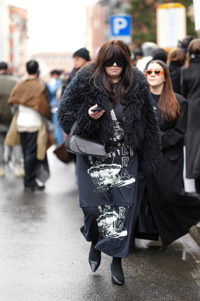 Guest wears sunglasses, a black fluffy faux fur coat, a long dress, outside Magliano, during the Milan Fashion Week Menswear Fall/Winter 2025-2026 on...