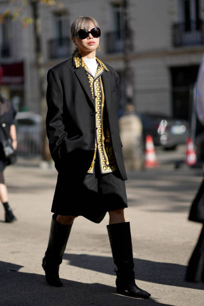 Guest wears sunglasses, a yellow shirt with printed patterns, a black oversized blazer jacket, outside Stella McCartney, during the Womenswear...