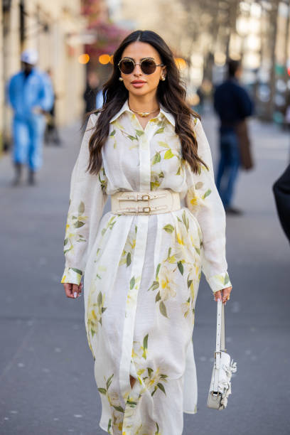 Guest wears white belted dress with floral print, white bag outside Zimmermann during the Womenswear Fall/Winter 2024/2025 as part of Paris Fashion...