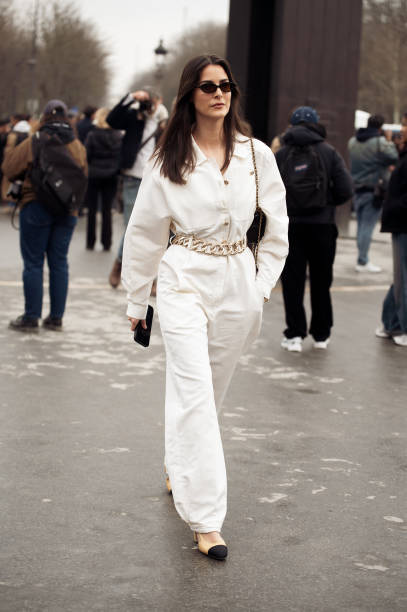 Guest wears white one piece with big chain belt and black Chanel bag outside the Chanel fashion show during the Womenswear Fall/Winter 2025/2026 as...