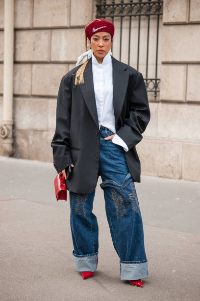 Guest wears white shirt, black blazer, decorated jeans, red heels and bag, red Nike beret, outside Miu Miu, during the Womenswear Fall/Winter...