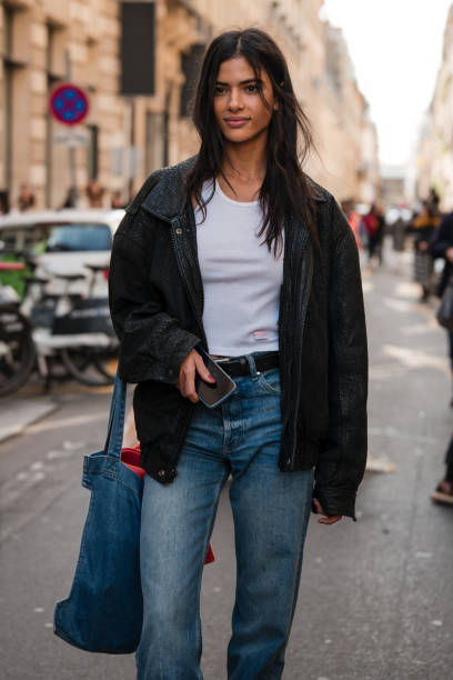 Guest wears white tank top, black leather jacket, blue jeans, denim tote bag, outside Zimmermann, during the Womenswear Fall/Winter 2024/2025 as part...