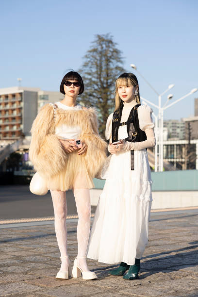 Guests are seen wearing a beige feather jacket and skirt, white boots and bag; a white dress with black vest during the Rakuten Fashion Week TOKYO...