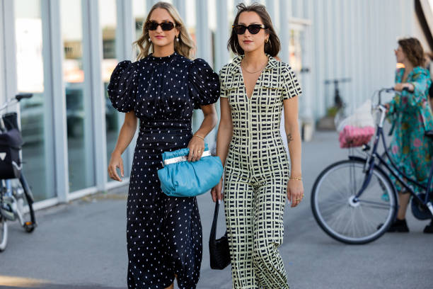 Guests seen wearing navy polka dot dress and guest wearing overall outside Munthe during Copenhagen Fashion Week Spring/Summer 2023 on August 11,...