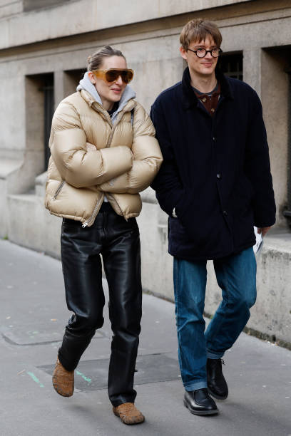 Guests wear beige bomber jacket, black leather pants, brown fur shoes, orange sunglasses , and blue jacket, blue jeans, black shoes , outside Issey...