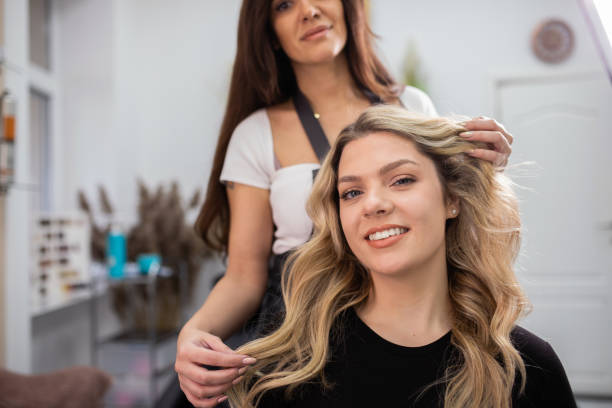 hairdresser blow drying female customers hair in hair salon. - hairstyle stock-fotos und bilder