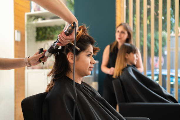 hairdresser using an electric curling iron with a client - hairstyle stock pictures, royalty-free photos & images