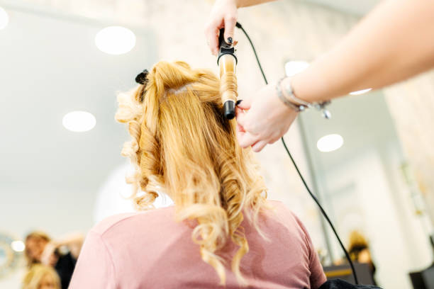 hairstylist using curling iron in salon - hairstyle stock pictures, royalty-free photos & images