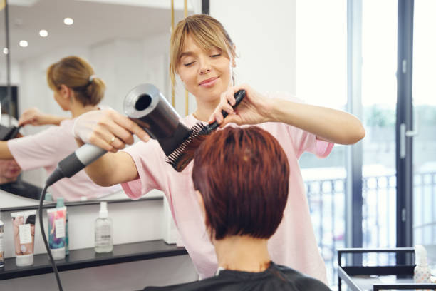 hairstylist working with client hairs with hairdryer - hairstyle stockfoto's en -beelden