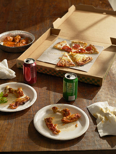 half-eaten pizza , buffalo wings and sodas - junk food stockfoto's en -beelden