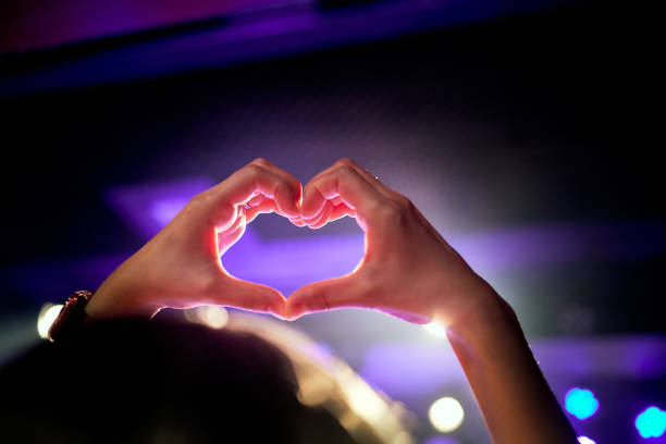 hand heart shape in the purple lighting of the concert hall. - concert stock pictures, royalty-free photos & images