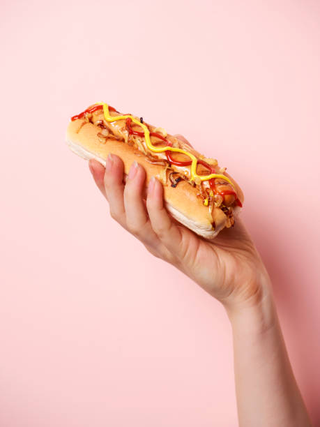 hand holding hotdog - junk food stock pictures, royalty-free photos & images