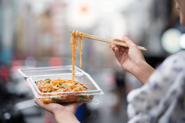 hand holding noodles with chopsticks on street - junk food stock pictures, royalty-free photos & images