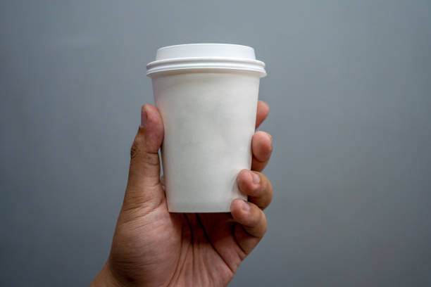 hand holds white disposable hot drink cup. - junk food stock pictures, royalty-free photos & images