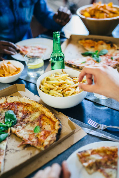 hand reaching for french fries on table - junk food stock pictures, royalty-free photos & images
