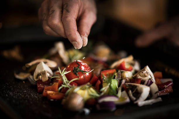 hand seasoning vegetables ona a baking tray - food stock pictures, royalty-free photos & images
