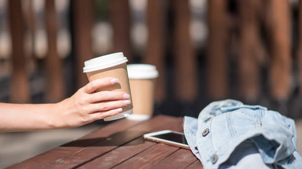 hand with a cup of coffee on a wooden background. a place for your ads. coffee day, coffee lovers. - junk food stock pictures, royalty-free photos & images