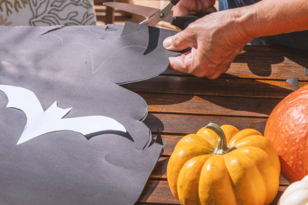 hands cutting black craft paper bats for halloween - garden decoration stock pictures, royalty-free photos & images