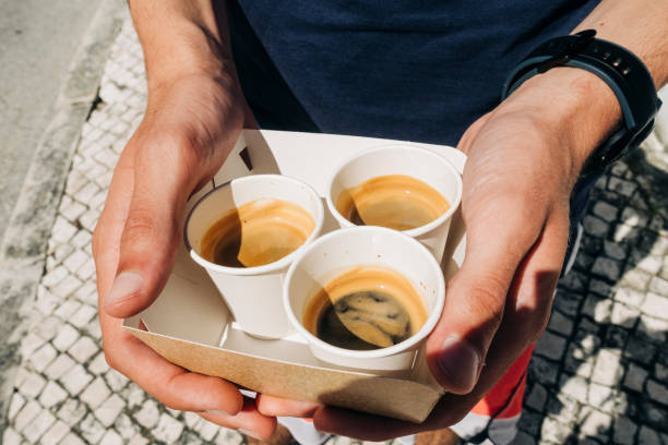 hands holding coffee cups: high angle view of young adult holding disposable coffee cups - junk food stock pictures, royalty-free photos & images