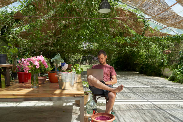 handsome blue eyes man working relaxed on his computer in the garden. - garden decoration stock pictures, royalty-free photos & images
