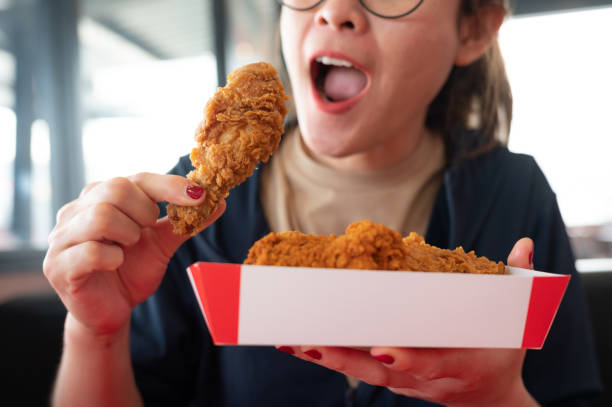 happiness woman holding a paper box with pieces of fried chicken before eating. - junk food stock pictures, royalty-free photos & images