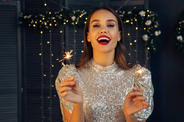 happy beautiful woman holding festive sparkler among christmas night - hairstyle stock pictures, royalty-free photos & images