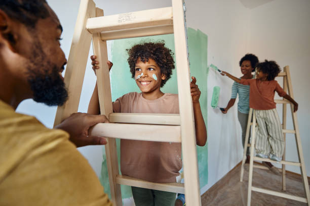 happy black father and son talking through ladders during home renovation process. - home decoration stock pictures, royalty-free photos & images
