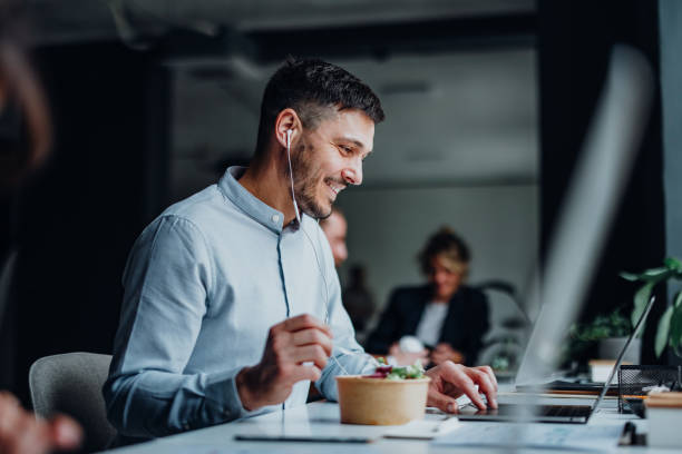 happy business man talking on a video call during a lunch break in a office - food stock pictures, royalty-free photos & images