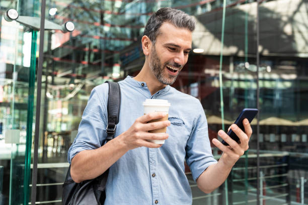 happy businessman looking at the smartphone in the city, berlin, germany - junk food stock pictures, royalty-free photos & images