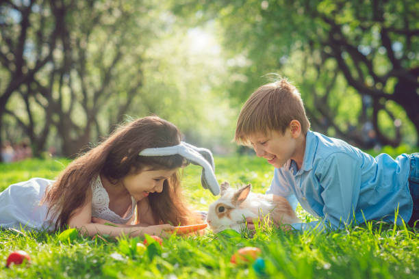 happy children playing with bunny on easter egg hunt - garden decoration stock pictures, royalty-free photos & images