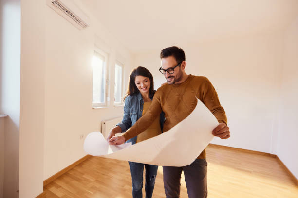 happy couple analyzing blueprints in their new apartment. - home decoration stock pictures, royalty-free photos & images