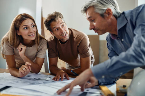 happy couple analyzing blueprints with an architect. - home decoration stock pictures, royalty-free photos & images