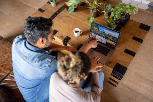 happy couple at home booking a trip online - travel stock pictures, royalty-free photos & images