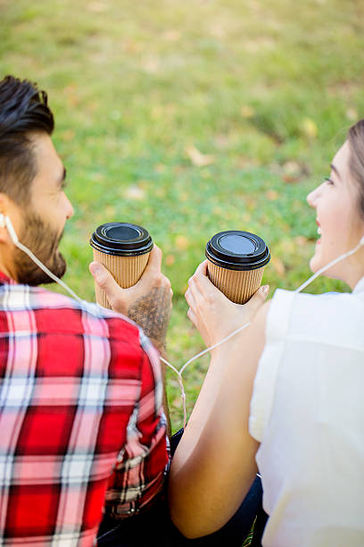 happy couple drinking coffee and listening music in the park - junk food stock pictures, royalty-free photos & images