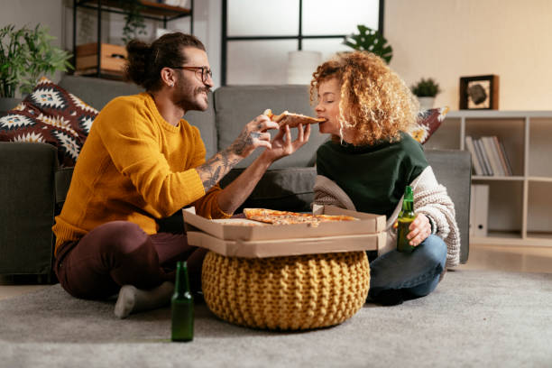 happy couple eating pizza at home. stock photo - junk food stock pictures, royalty-free photos & images