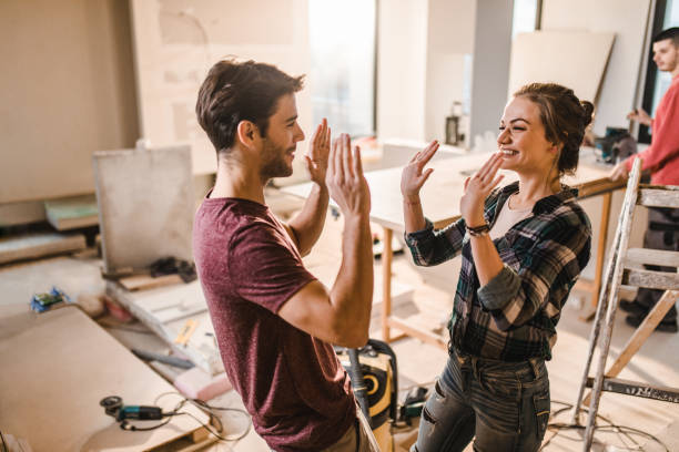 happy couple giving each other high-five at their renovating apartment. - home decoration stock pictures, royalty-free photos & images