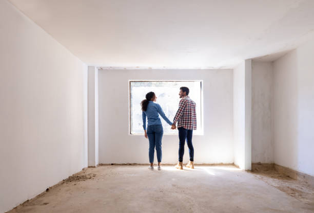 happy couple holding hands at a construction site while building their house - home decoration stock pictures, royalty-free photos & images