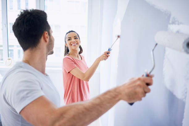 happy couple painting wall in apartment together - home decoration stock pictures, royalty-free photos & images