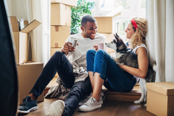 happy couple playing with dog while sitting at doorway in new house - home decoration stock pictures, royalty-free photos & images