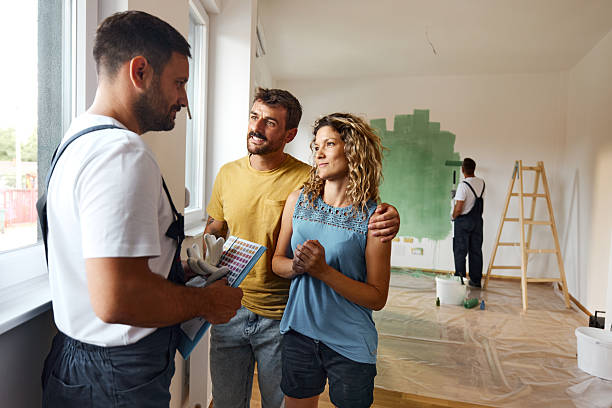 happy couple talking to their house painter inside of renovating apartment. - home decoration stock pictures, royalty-free photos & images