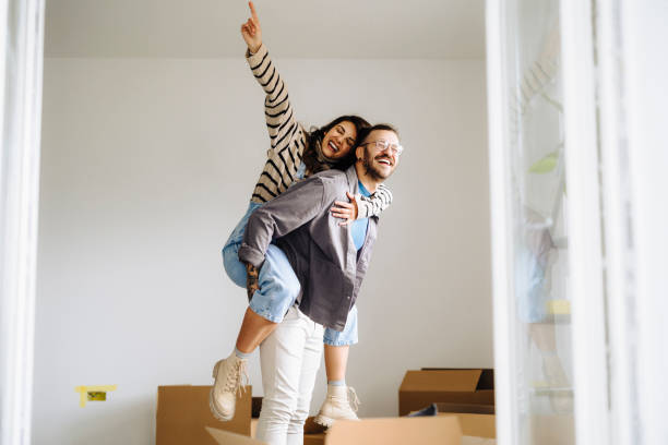 happy couple with arms stretched out enjoying in new home - home decoration stock pictures, royalty-free photos & images