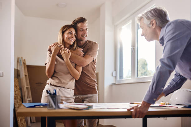 happy embraced couple talking about blueprints with an architect. - home decoration stock pictures, royalty-free photos & images