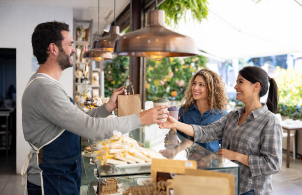 happy female friends buying take out food at a coffee shop - junk food stock pictures, royalty-free photos & images